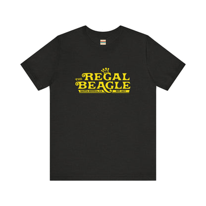 The Printify Regal Beagle - Three's Company Unisex Jersey Short Sleeve Tee, in black, showcases "The Regal Beagle, Santa Monica, CA, Est. 1977" text in a yellow vintage-style font. Crafted from 100% Airlume combed cotton for superior comfort.