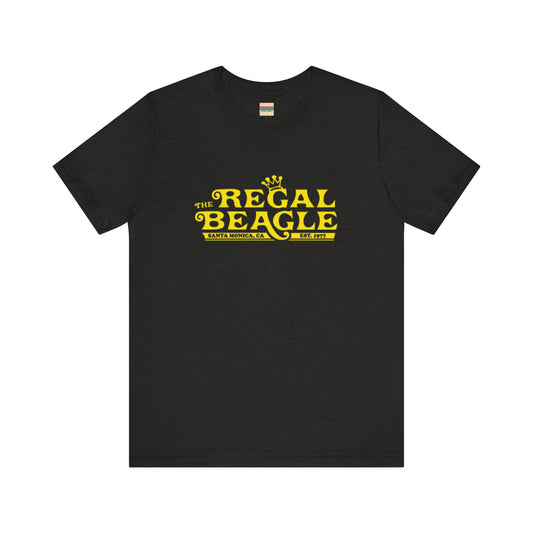 The Printify Regal Beagle - Three's Company Unisex Jersey Short Sleeve Tee, in black, showcases "The Regal Beagle, Santa Monica, CA, Est. 1977" text in a yellow vintage-style font. Crafted from 100% Airlume combed cotton for superior comfort.