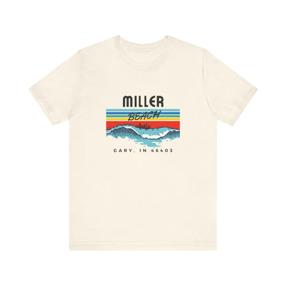 The Miller Beach 46403 Surf Style - Unisex Jersey Short Sleeve Tee by Printify features a retro surf-inspired design on a yellow background. The shirt displays "MILLER BEACH" above waves with a skyline illustration, while "Cary, IN 46403" is printed below the waves. The vibrant design also includes colorful stripes in shades of blue, red, and orange.