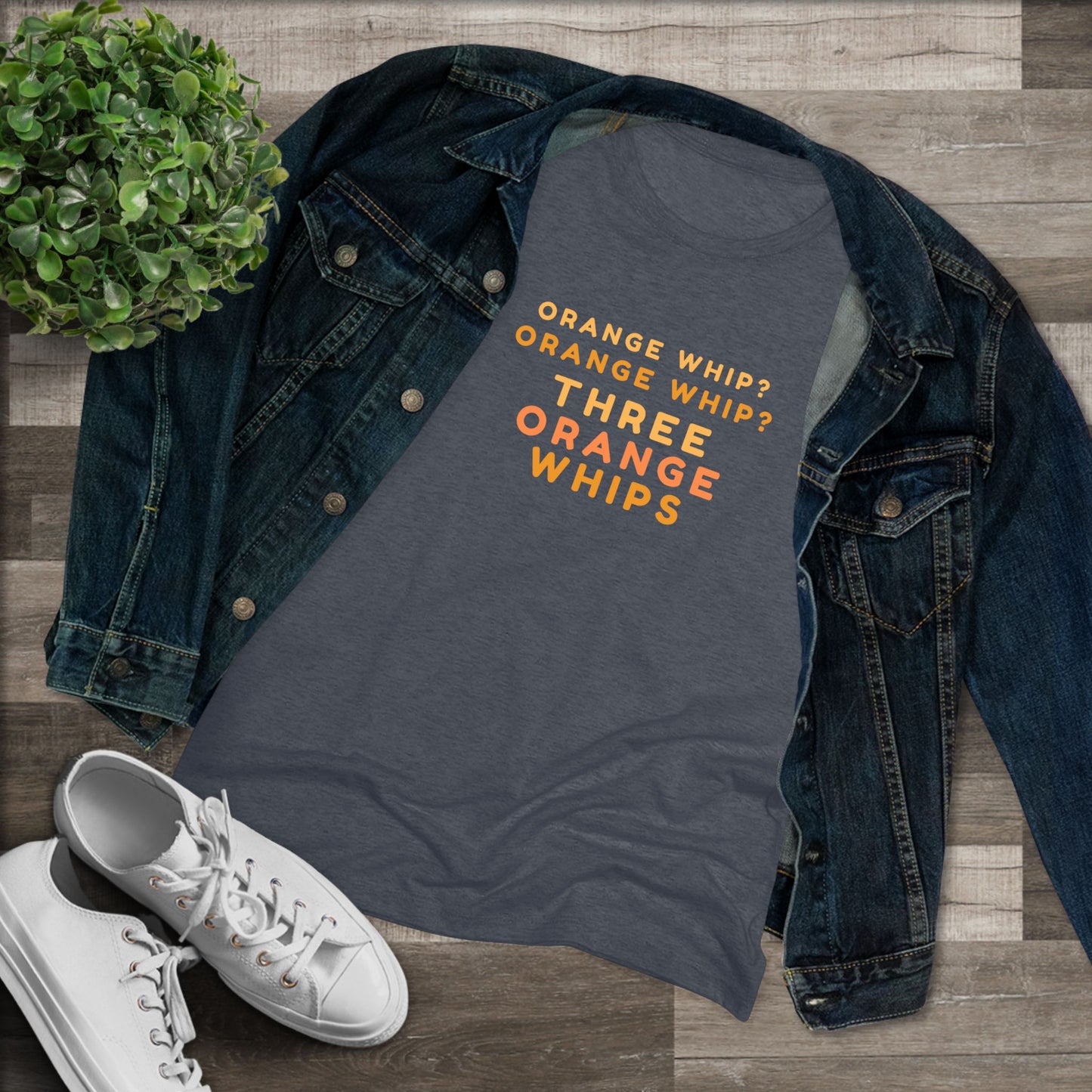 This Blues Brothers women's triblend tee from Printify features a dark gray vintage look with the text "ORANGE WHIP? ORANGE WHIP? THREE ORANGE WHIPS" printed in bright orange and yellow in the center. With a round neck and short sleeves, it's perfect for that retro vibe.