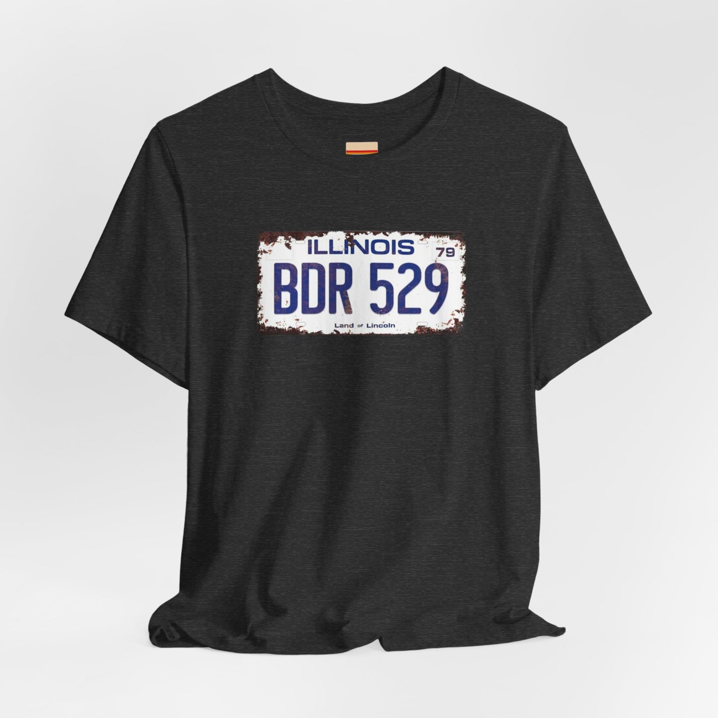 The Printify Blues Brothers BDR 529 License Plate Unisex Jersey Short Sleeve Tee showcases a vintage Illinois license plate graphic with "BDR 529" prominently displayed, as famously seen in the Blues Brothers film. The design includes "Illinois" and "Land of Lincoln" above and below the numbers, with a weathered, rustic look that enhances its retro appeal.