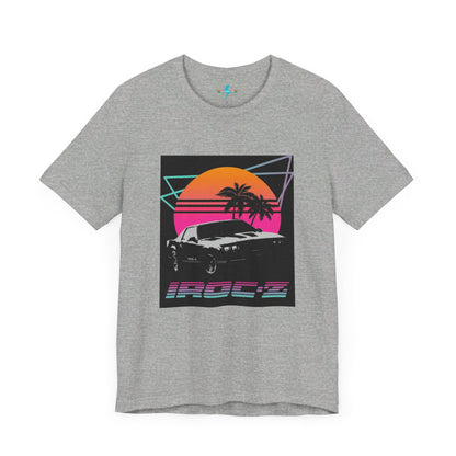 A Chevrolet Camaro iRoc Z Z28 T-Shirt 1980's by Printify, featuring a retro design with a black car, palm trees, and a sun setting in the background. The design includes geometric lines in neon colors and the text "IROC-Z" at the bottom, perfect for fans of the 1980s Chevy Camaro.