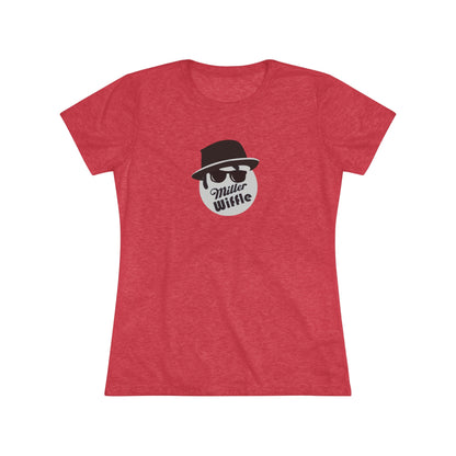 A cozy red t-shirt, the Miller Wiffel Ball - Blues Brothers - Women's Triblend Tee by Printify, features a graphic of a masked face wearing a fedora hat and sunglasses, along with the text "Miller Wiffle." The t-shirt is displayed on a wooden floor, paired with a denim jacket, white sneakers, and a potted green plant to create a vintage look.