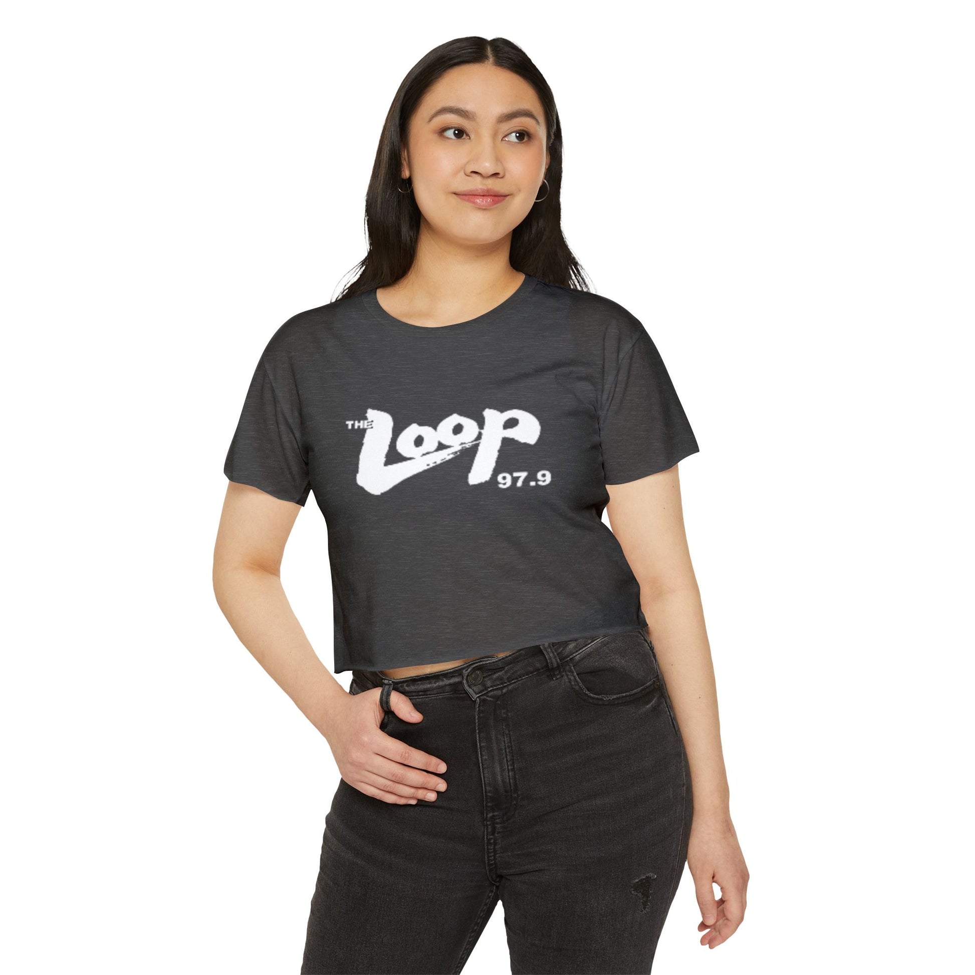 Printify's Women's Festival Crop Top features a grey design with short sleeves and a round neckline. The crop top displays the text "The Loop 97.9" in white, with the word "Loop" styled in a brushstroke-like font—ideal for fans of Chicago’s iconic rock radio station who appreciate retro fashion.