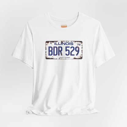 The Printify Blues Brothers BDR 529 License Plate Unisex Jersey Short Sleeve Tee showcases a vintage Illinois license plate graphic with "BDR 529" prominently displayed, as famously seen in the Blues Brothers film. The design includes "Illinois" and "Land of Lincoln" above and below the numbers, with a weathered, rustic look that enhances its retro appeal.