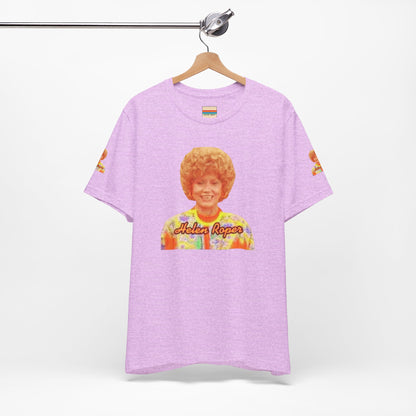 A lavender-colored Helen (Mrs.) Roper Three's Company - Unisex Jersey Short Sleeve Tee by Printify is hanging on a wooden hanger against a white background. This T-shirt features an image of a smiling person with curly hair wearing a colorful blouse, with the text "Helen Roper" underneath the image. Both sleeves have identical designs, making it perfect Three's Company merchandise.