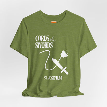 The SoCool Podcast - Cords & Swords Store T-Shirt by Printify is a vintage-inspired blue shirt that showcases a white graphic with the text "Cords & Swords" above illustrations of a crossed power cord and sword, along with "St. Joseph, MI" beneath. Ideal for tech enthusiasts, this design is centered on the front against a plain white background.