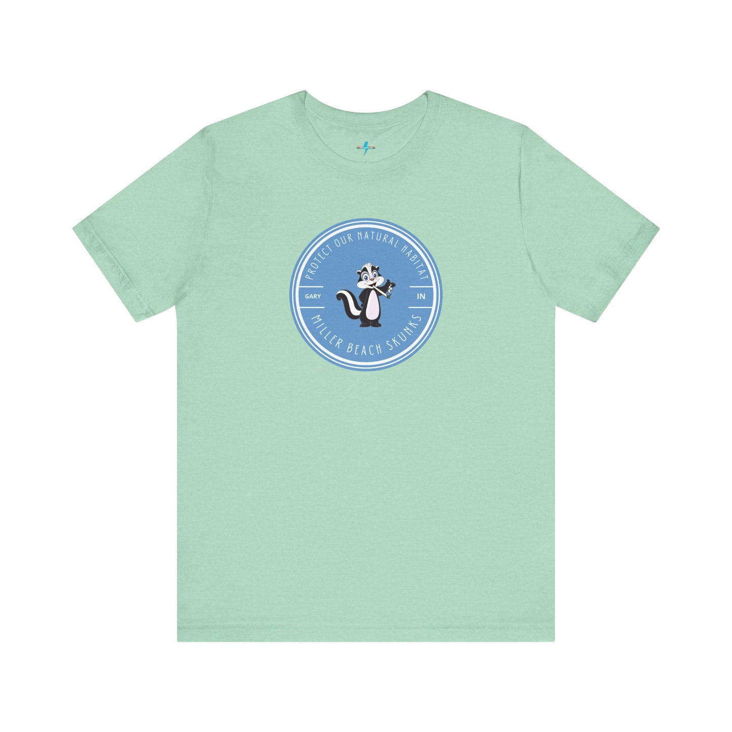 The Printify Miller Beach Skunks - Unisex Jersey Short Sleeve Tee is a gray T-shirt that features a circular blue logo at the center. Inside the logo, there is an illustration of a skunk with the text "Protect Our Habitat" and "Miller Beach Skunks" around the border, promoting environmental consciousness. The upper left part of the logo reads "Gary, IN.