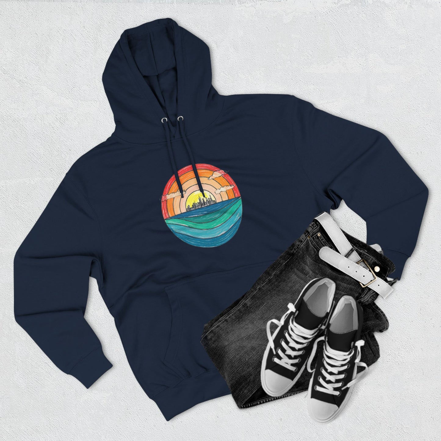 The Miller Beach Abstract - Three-Panel Fleece Hoodie by Printify is a premium light gray pullover featuring a vibrant circular front design. It showcases an abstract sunset-over-ocean scene with blue waters, an orange to red gradient sky, and a city skyline silhouette. Made from soft combed ring-spun cotton and lined with cozy fleece for extra warmth.