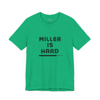 A unisex jersey short sleeve tee from Printify in burnt orange features the bold black text "MILLER IS HARD" on the chest, with "GARY, IN" written beneath in smaller black font. Perfect for showcasing Miller Beach's iconic spirit, this t-shirt is displayed against a plain white background.