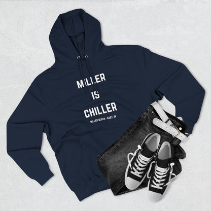 The Miller is Chiller - Miller Beach Three-Panel Fleece Hoodie from Printify features bold white text reading "MILLER IS CHILLER" on the front, with smaller text below stating "MILLER BEACH - GARY, IN." This comfortable black hoodie includes a front pocket and drawstrings.