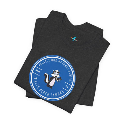 The Printify Miller Beach Skunks - Unisex Jersey Short Sleeve Tee is a gray T-shirt that features a circular blue logo at the center. Inside the logo, there is an illustration of a skunk with the text "Protect Our Habitat" and "Miller Beach Skunks" around the border, promoting environmental consciousness. The upper left part of the logo reads "Gary, IN.