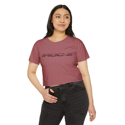 A grey, short-sleeve, rounded-neckline Women's Festival Crop Top by Printify, featuring "IROC-Z" printed in bold black letters across the chest. Perfect for any festival, this Chevrolet Iroc Z-inspired top from the 1980s stands out against a plain white background.