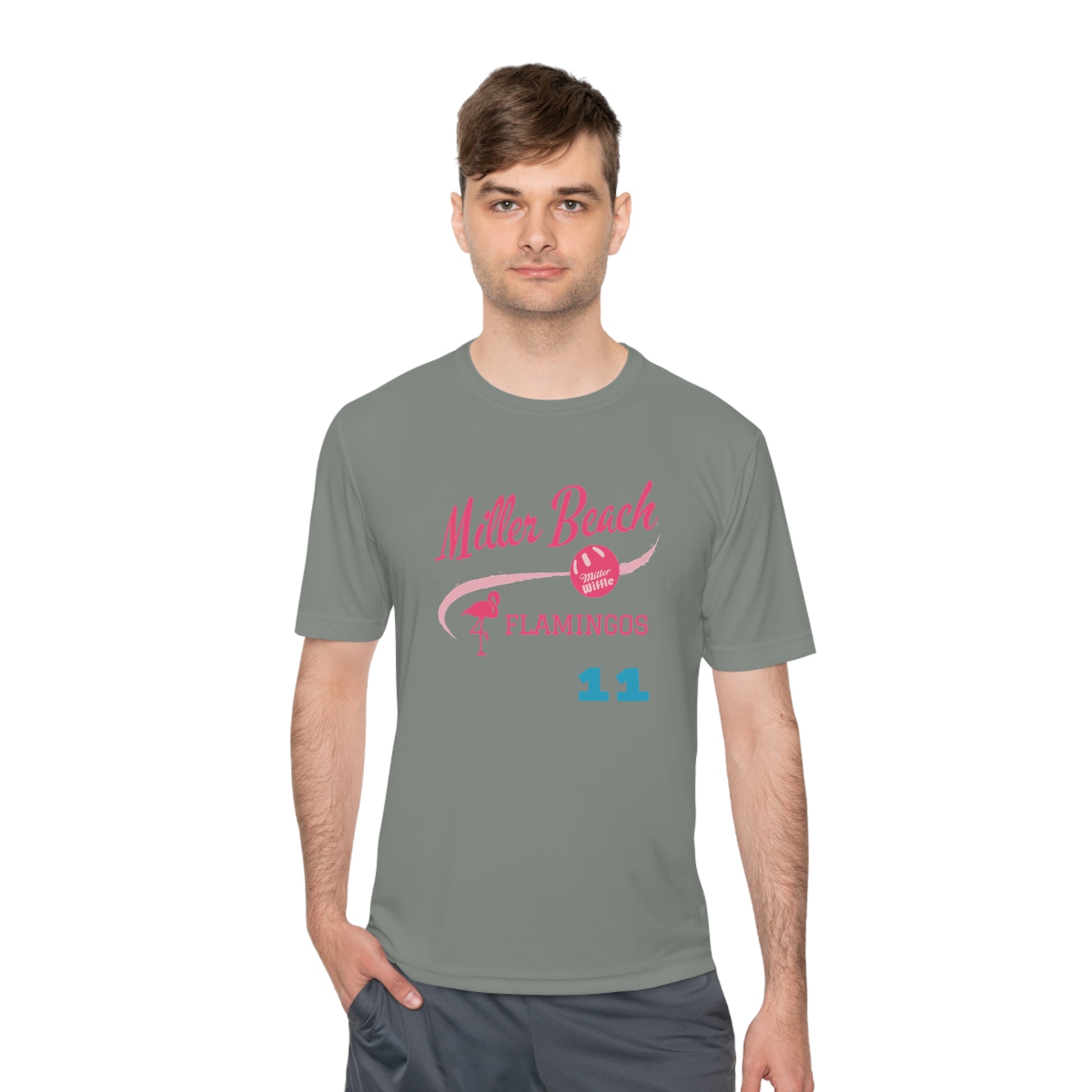 The Miller Beach Flamingos - Poncin 11 Unisex Moisture Wicking Tee by Printify features a beige shirt with "Miller Beach" in pink script, accompanied by a small illustration of a flamingo and volleyball. Below this design, the word "FLAMINGOS" is displayed in pink, with the number "11" appearing in blue near the bottom. Made from Sport-Tek PosiCharge Competitor Tee fabric, this custom moisture-wicking shirt ensures you stay cool and stylish.