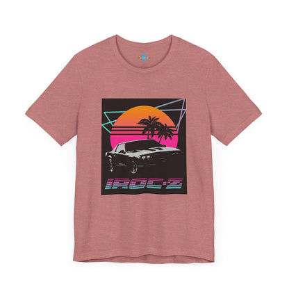 A Chevrolet Camaro iRoc Z Z28 T-Shirt 1980's by Printify, featuring a retro design with a black car, palm trees, and a sun setting in the background. The design includes geometric lines in neon colors and the text "IROC-Z" at the bottom, perfect for fans of the 1980s Chevy Camaro.