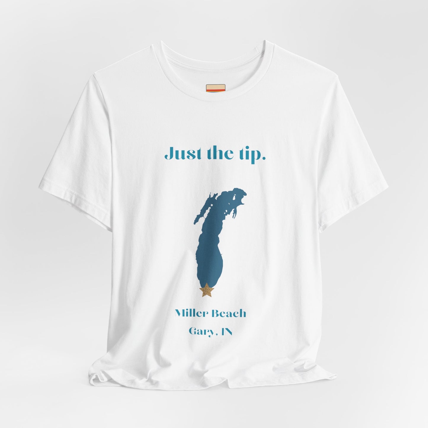 The Just the Tip - Miller Beach Unisex Jersey Short Sleeve Tee by Printify in yellow showcases text and a graphic design. The top displays "Just the tip" above a blue silhouette reminiscent of Indiana. At the bottom, it reads "Miller Beach" and "Gary, IN." Made from soft Airlume combed cotton, this tee offers both comfort and style.