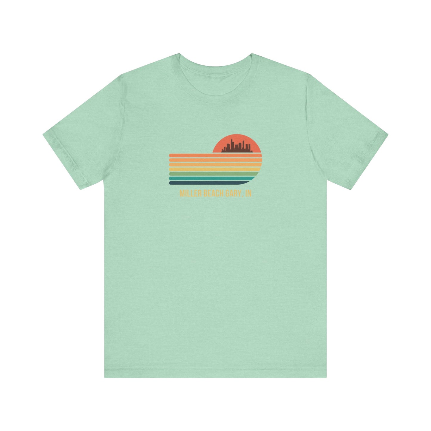 Introducing the Miller Beach Gary, IN Sunset Gradient - Unisex Jersey Short Sleeve Tee by Printify. This stylish blue T-shirt features a circular sunset graphic on the chest, showcasing a black city skyline silhouette against an orange-red sunset with horizontal stripes in green, yellow, and orange. Below the graphic reads "MILLER BEACH GARY, IN." Crafted from soft cotton for extra beachy charm.