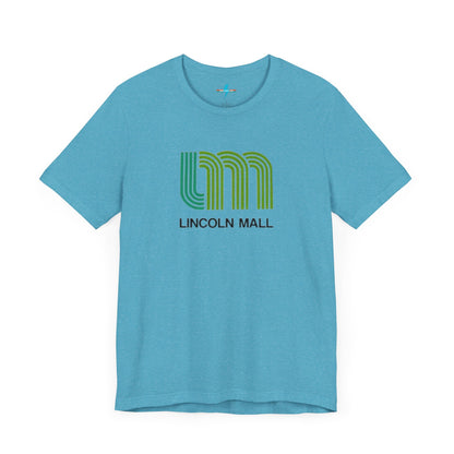 A light green unisex jersey short sleeve tee by Printify features "LINCOLN MALL" written under a retro-styled green and blue curved line design, celebrating the 70s and 80s shopping era in Lincoln Mall Matteson.