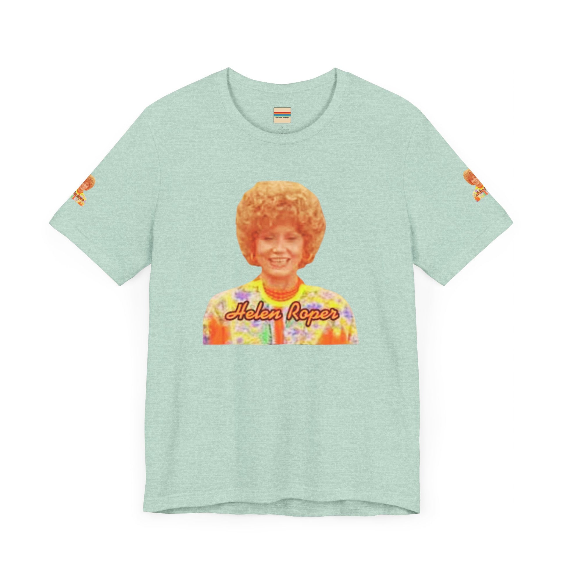 A lavender-colored Helen (Mrs.) Roper Three's Company - Unisex Jersey Short Sleeve Tee by Printify is hanging on a wooden hanger against a white background. This T-shirt features an image of a smiling person with curly hair wearing a colorful blouse, with the text "Helen Roper" underneath the image. Both sleeves have identical designs, making it perfect Three's Company merchandise.