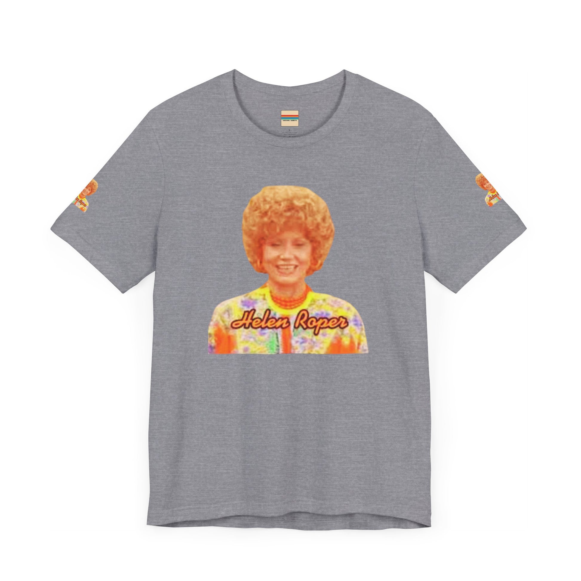 A lavender-colored Helen (Mrs.) Roper Three's Company - Unisex Jersey Short Sleeve Tee by Printify is hanging on a wooden hanger against a white background. This T-shirt features an image of a smiling person with curly hair wearing a colorful blouse, with the text "Helen Roper" underneath the image. Both sleeves have identical designs, making it perfect Three's Company merchandise.