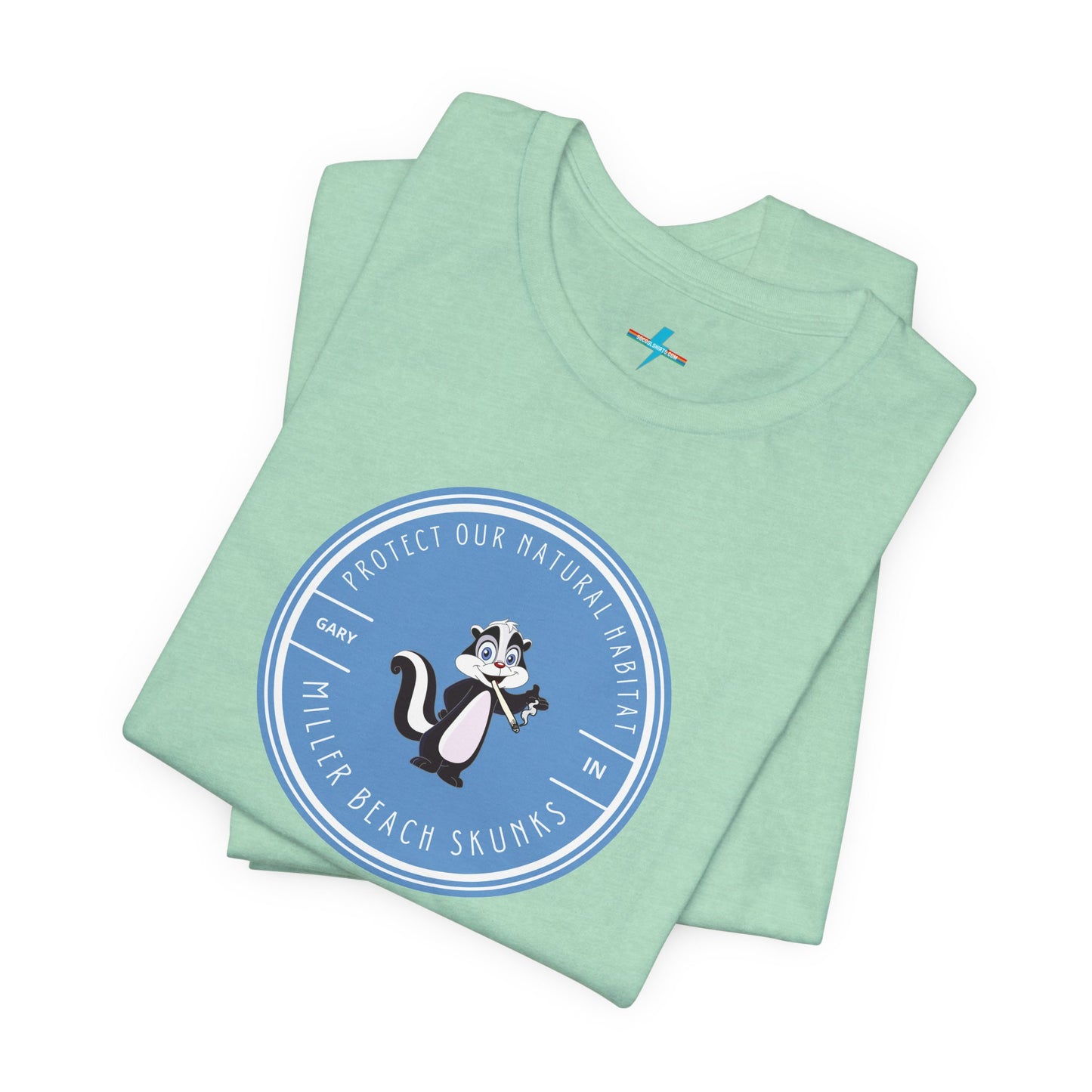 The Printify Miller Beach Skunks - Unisex Jersey Short Sleeve Tee is a gray T-shirt that features a circular blue logo at the center. Inside the logo, there is an illustration of a skunk with the text "Protect Our Habitat" and "Miller Beach Skunks" around the border, promoting environmental consciousness. The upper left part of the logo reads "Gary, IN.