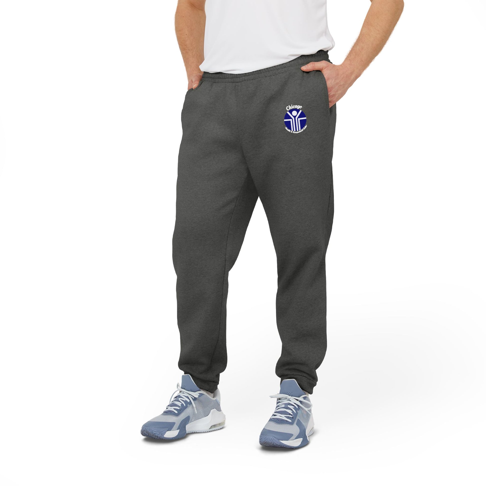 Gray Adidas unisex fleece joggers from Printify, showcasing the classic Chicago Health Clubs - Bally's 1980s logo on the left thigh and a blue and white emblem on the right. Crafted from sustainable BCI cotton, these joggers feature an elastic waistband and cuffs for maximum comfort.