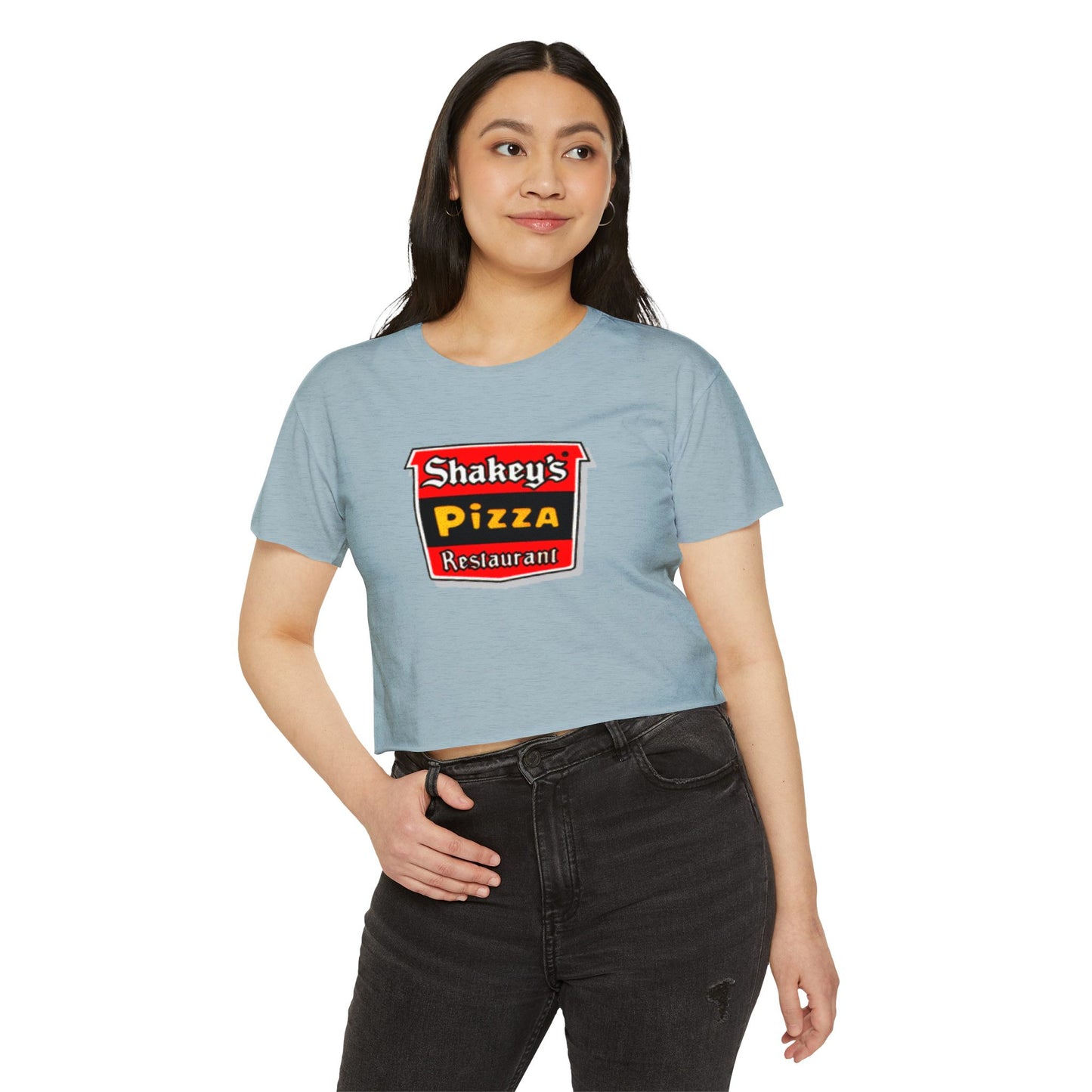 The Shakey's Pizza - Women's Festival Crop Top from Printify is a light blue garment that proudly displays the iconic Shakey's Pizza logo on the chest. Featuring retro-style red and black signage with text in white, yellow, and red that reads "Shakey's Pizza Restaurant," this crop top exudes a vintage-inspired charm.