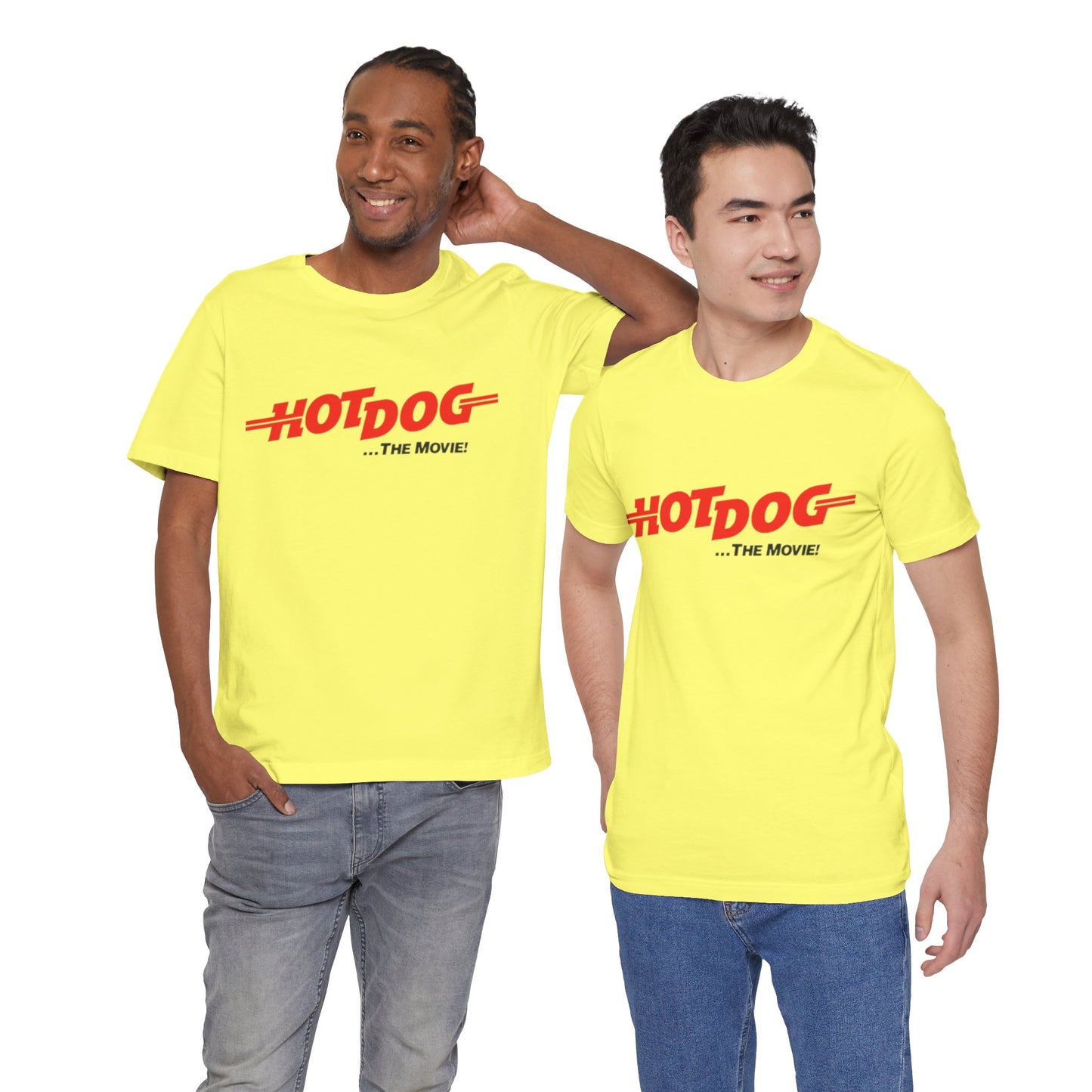 A smiling man and woman interact while wearing matching yellow "Hot Dog The Movie 1984 - Unisex Jersey Short Sleeve Tee" by Printify, featuring bold red "HOT DOG THE MOVIE" text. Their vibrant tees perfectly complement their blue jeans, with the man casually having his hands in his pockets and the woman resting one hand on his shoulder.