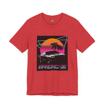 A Chevrolet Camaro iRoc Z Z28 T-Shirt 1980's by Printify, featuring a retro design with a black car, palm trees, and a sun setting in the background. The design includes geometric lines in neon colors and the text "IROC-Z" at the bottom, perfect for fans of the 1980s Chevy Camaro.