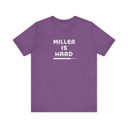 The Miller is Hard - White Letters - Unisex Jersey Short Sleeve Tee by Printify features a rust-colored design with "MILLER IS HARD" printed in bold, white capitals on the front. Below, "GARY, IN." is added in smaller font. This simple yet striking shirt evokes the spirit of Miller Beach with no additional graphics or patterns.