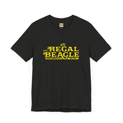 The Printify Regal Beagle - Three's Company Unisex Jersey Short Sleeve Tee, in black, showcases "The Regal Beagle, Santa Monica, CA, Est. 1977" text in a yellow vintage-style font. Crafted from 100% Airlume combed cotton for superior comfort.