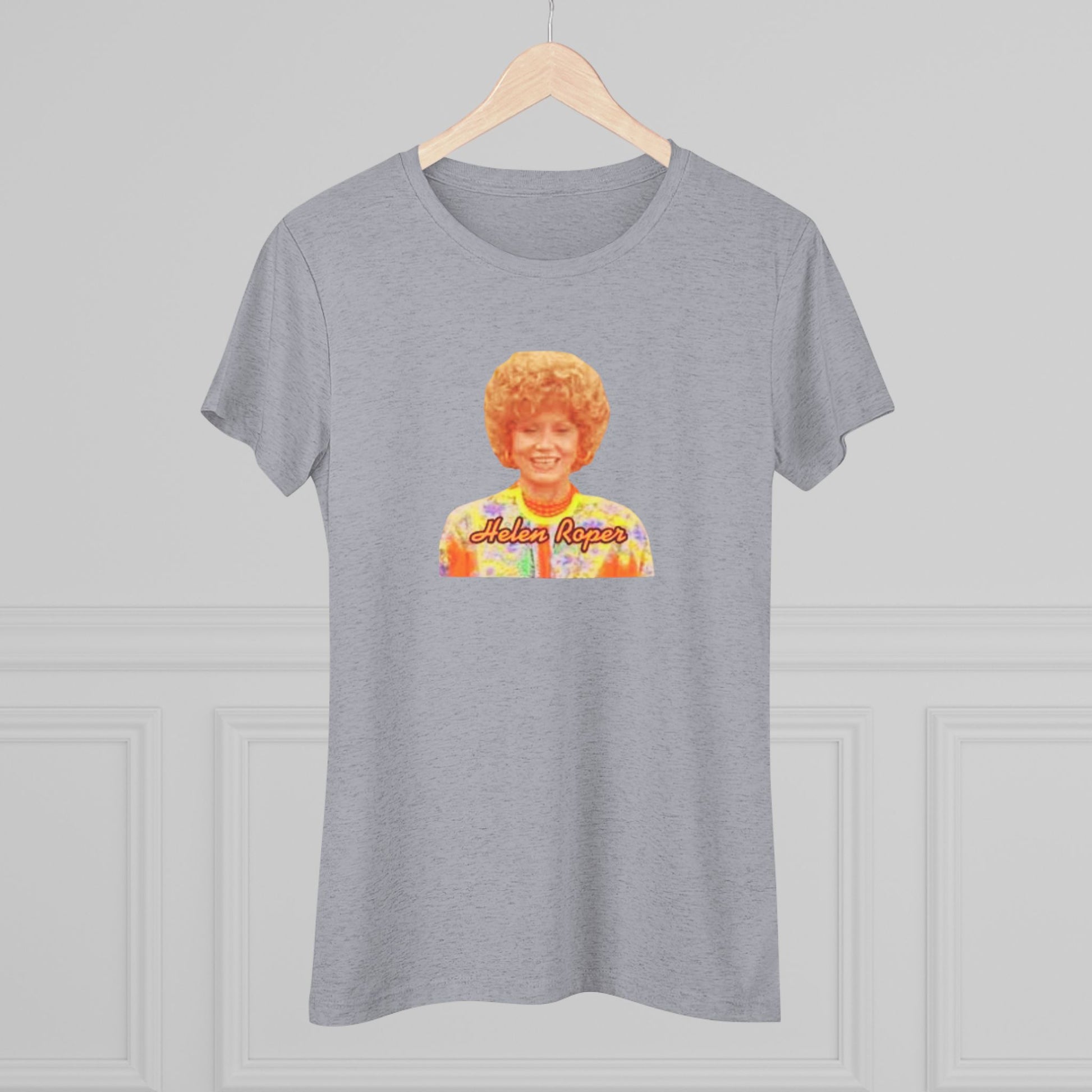 A Women's Triblend Tee by Printify, titled "Helen Roper - Three's Company," features a red design with an illustration of a smiling person with curly hair and colorful clothing. Below the illustration, the text "Helen Roper" is written in a bold, retro font, capturing the essence of vintage TV humor.