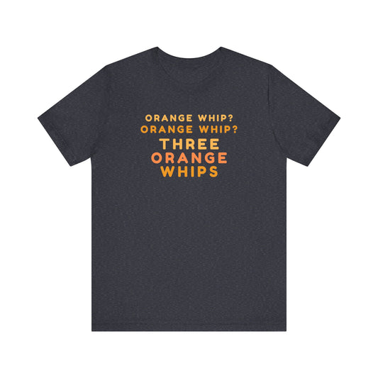 A short-sleeve, dark gray tee from Printify features the text "ORANGE WHIP? ORANGE WHIP? THREE ORANGE WHIPS" in bold orange, uppercase letters on the front. This classic unisex jersey shirt, named "Three Orange Whips - The Blues Brothers - Unisex Jersey Short Sleeve Tee," pays homage to a famous scene from The Blues Brothers movie.