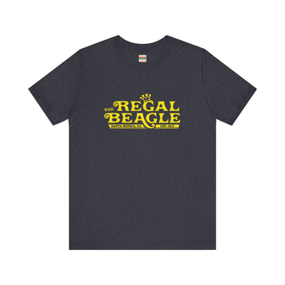 The Printify Regal Beagle - Three's Company Unisex Jersey Short Sleeve Tee, in black, showcases "The Regal Beagle, Santa Monica, CA, Est. 1977" text in a yellow vintage-style font. Crafted from 100% Airlume combed cotton for superior comfort.