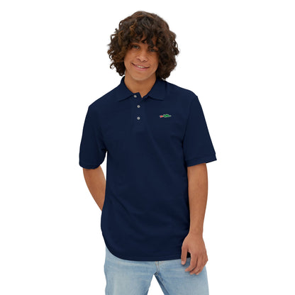 A person with curly hair wearing a navy blue Printify Braggin' Dragon - 1980s Sears Men's Piqué Polo, featuring a small embroidered dragon logo on the left chest, smiles against a plain white background.