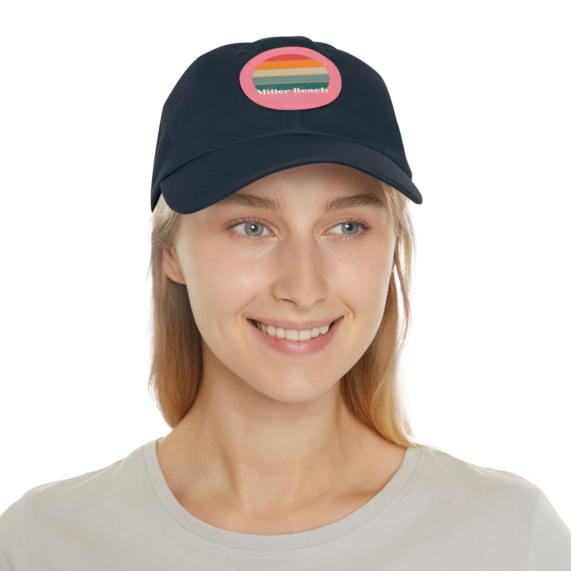 The Miller Beach Retro Sunset - Dad Hat with Leather Patch (Round) by Printify is a pink baseball cap crafted from bio-washed chino twill for added comfort. It features a PU leather patch adorned with horizontal stripes in red, orange, yellow, green, and blue. Below the stripes, "Miller Beach" is embroidered in white. An adjustable strap at the back ensures a perfect fit.