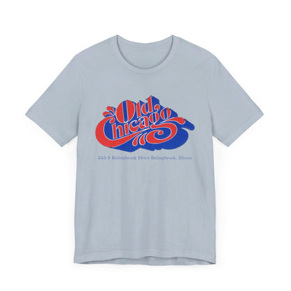 The "Old Chicago Mall Bolingbrook 1980s Retro - Unisex Jersey Short Sleeve Tee" from Printify is a gray T-shirt showcasing a vintage design with the text "Old Chicago" in blue and red. Beneath the main text, the address "355 S. Bolingbrook Drive, Bolingbrook, Illinois" appears in smaller font, evoking 80s nostalgia of the Old Chicago Mall. The shirt is displayed against a white background.