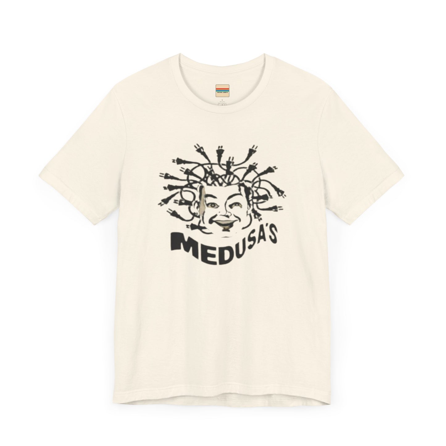 A cream-colored unisex jersey short sleeve tee from Printify, titled "Medusa's 1980s Dance Club Chicago," features a black and white illustration of a cartoonish Medusa head. The soft cotton design showcases numerous snakes as hair with a smiling face. Below, the word "MEDUSA'S" is printed in bold, playful font.