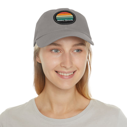 The Miller Beach Retro Sunset - Dad Hat with Leather Patch (Round) by Printify is a pink baseball cap crafted from bio-washed chino twill for added comfort. It features a PU leather patch adorned with horizontal stripes in red, orange, yellow, green, and blue. Below the stripes, "Miller Beach" is embroidered in white. An adjustable strap at the back ensures a perfect fit.