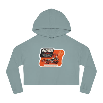 The Raceway Park - Blue Island, IL Women's Cropped Hooded Sweatshirt by Printify features an eye-catching camouflage pattern with a bold red and black "Raceway Park" graphic. Perfect for car enthusiasts, it is adorned with images of cars and text that celebrate a fictional race and hot rod theme, capturing the spirit of Blue Island racers.