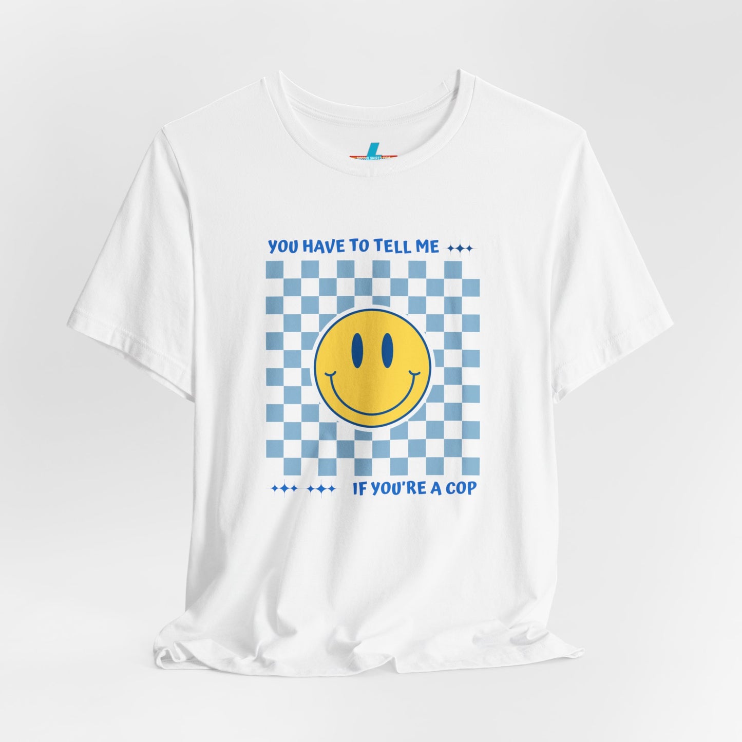 A light yellow unisex jersey short sleeve tee from Printify featuring a blue and yellow checkerboard pattern with a large yellow smiley face in the center. The shirt displays blue text above and below the pattern that reads, "You have to tell me if you're a cop." It's made from 100% Airlume combed and ring-spun cotton.