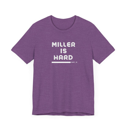 The Miller is Hard - White Letters - Unisex Jersey Short Sleeve Tee by Printify features a rust-colored design with "MILLER IS HARD" printed in bold, white capitals on the front. Below, "GARY, IN." is added in smaller font. This simple yet striking shirt evokes the spirit of Miller Beach with no additional graphics or patterns.