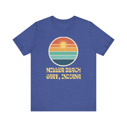The Miller Beach Sunshine - Unisex Jersey Short Sleeve Tee by Printify is a blue tee with a retro design featuring a graphic of a sunset over striped waves. Made from 100% Airlume cotton, the text below the graphic reads "Miller Beach Gary, Indiana" in a stylized font. Our sustainable manufacturing ensures top quality and eco-friendly practices.