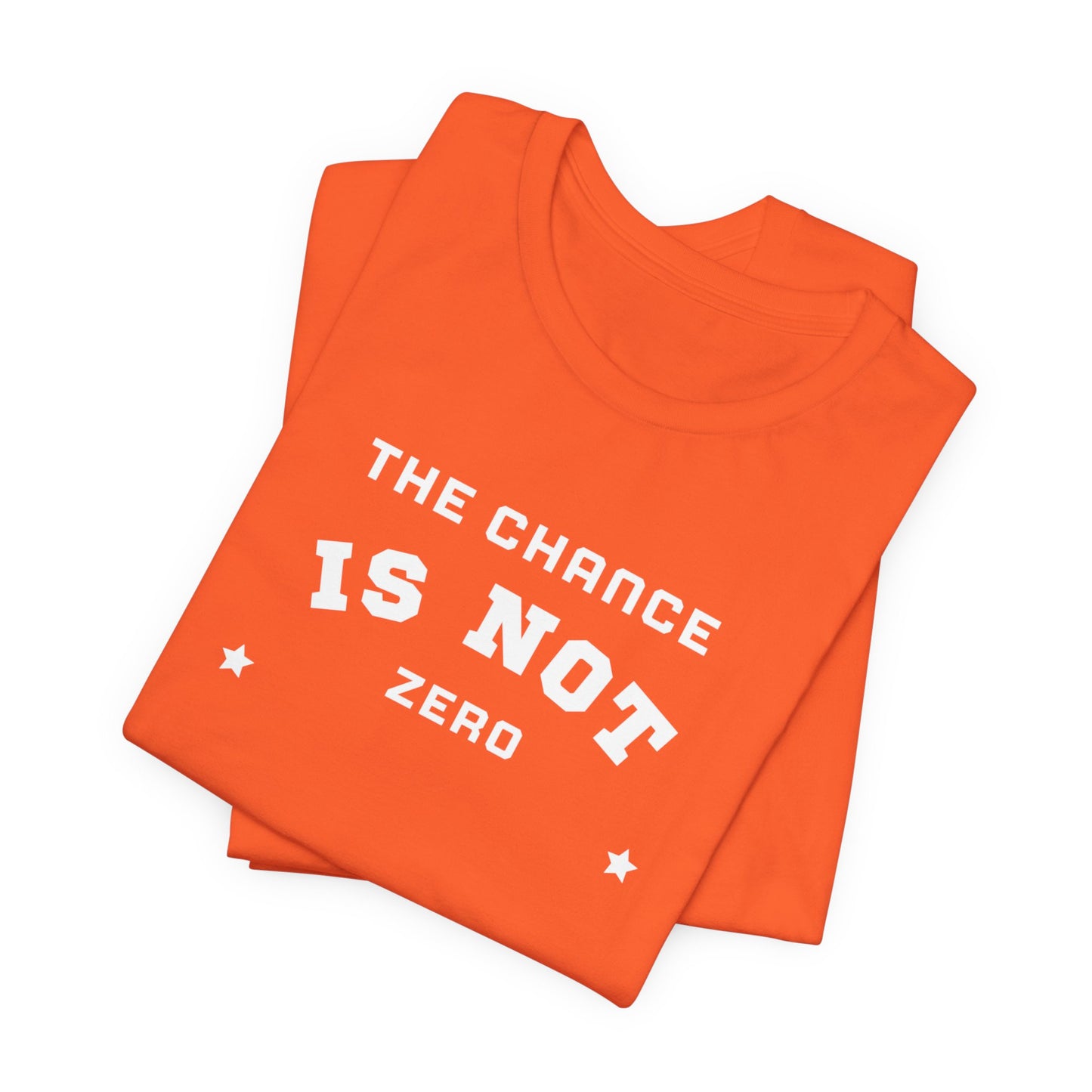 Folded light red Unisex Jersey Short Sleeve Tee from Printify, featuring bold white text that reads "THE CHANCE IS NOT ZERO" along with two star illustrations. This motivational T-shirt, made from breathable fabric, is neatly stacked with another identical shirt underneath.