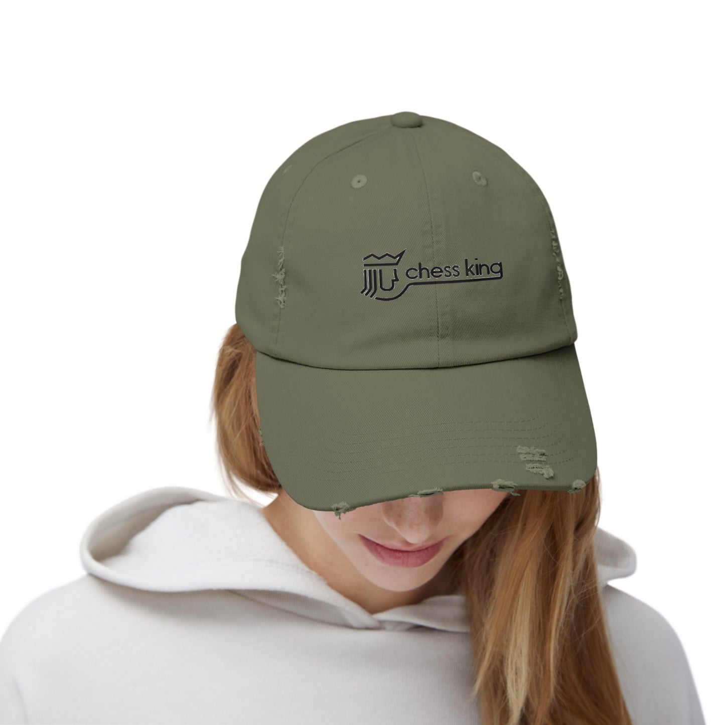 The 1980s Chess King Clothing Store Logo - Unisex Distressed Cap by Printify is a beige baseball cap made from 100% cotton twill. It features intentional distress details and a logo with a crown and rook piece, along with the text "chess king" embroidered on the front, making it a stylish choice for custom caps enthusiasts.