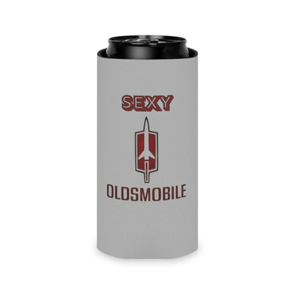 The Sexy Oldsmobile Koozie by Printify features "SEXY" in red at the top on a gray background, followed by the Oldsmobile logo and the word "OLDSMOBILE" below it. At the bottom, there's a blue and red logo reading "SOCOOLSHIRTS.COM." This koozie has an indentation designed to hold a can securely.