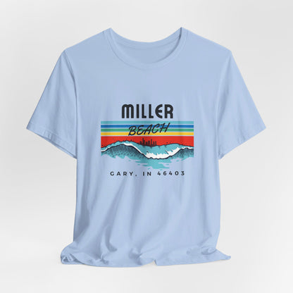 The Miller Beach 46403 Surf Style - Unisex Jersey Short Sleeve Tee by Printify features a retro surf-inspired design on a yellow background. The shirt displays "MILLER BEACH" above waves with a skyline illustration, while "Cary, IN 46403" is printed below the waves. The vibrant design also includes colorful stripes in shades of blue, red, and orange.