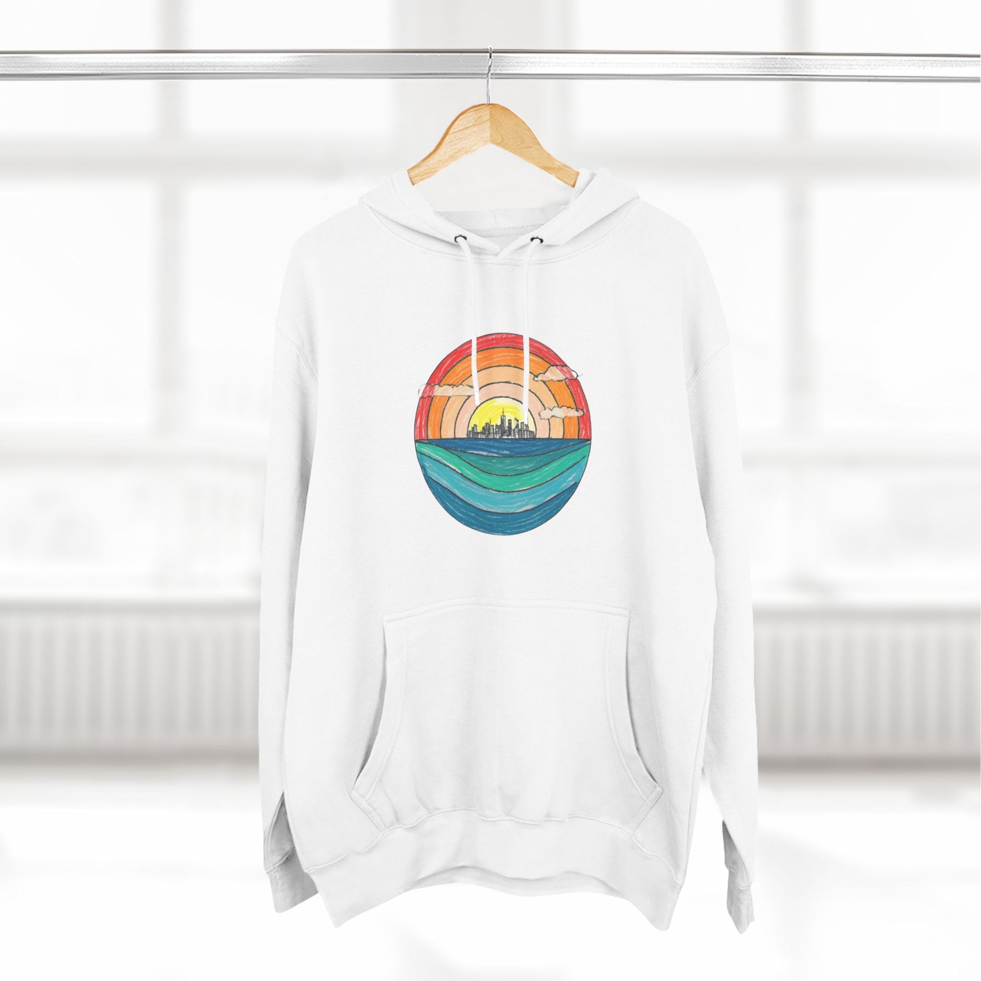 The Miller Beach Abstract - Three-Panel Fleece Hoodie by Printify is a premium light gray pullover featuring a vibrant circular front design. It showcases an abstract sunset-over-ocean scene with blue waters, an orange to red gradient sky, and a city skyline silhouette. Made from soft combed ring-spun cotton and lined with cozy fleece for extra warmth.