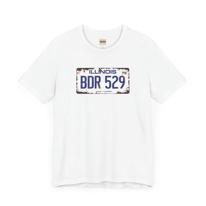 The Printify Blues Brothers BDR 529 License Plate Unisex Jersey Short Sleeve Tee showcases a vintage Illinois license plate graphic with "BDR 529" prominently displayed, as famously seen in the Blues Brothers film. The design includes "Illinois" and "Land of Lincoln" above and below the numbers, with a weathered, rustic look that enhances its retro appeal.