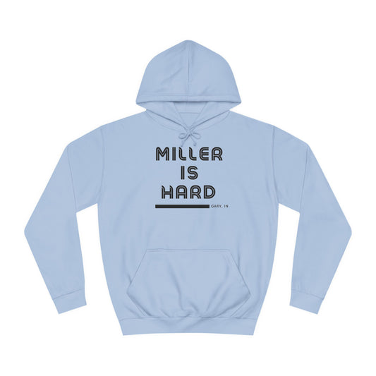 A light blue unisex college hoodie from Printify features the bold black text "MILLER IS HARD" on the front, with "GARY, IN." in smaller letters below. This hoodie is equipped with a front pocket and adjustable drawstrings, ideal for those who appreciate the Miller Beach style.